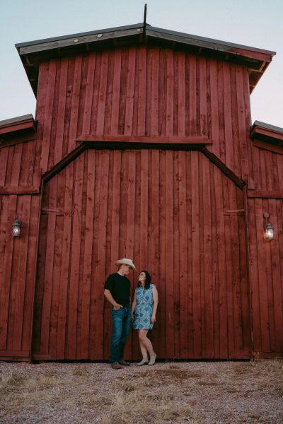 couple by big red barn doing modern homesteading
