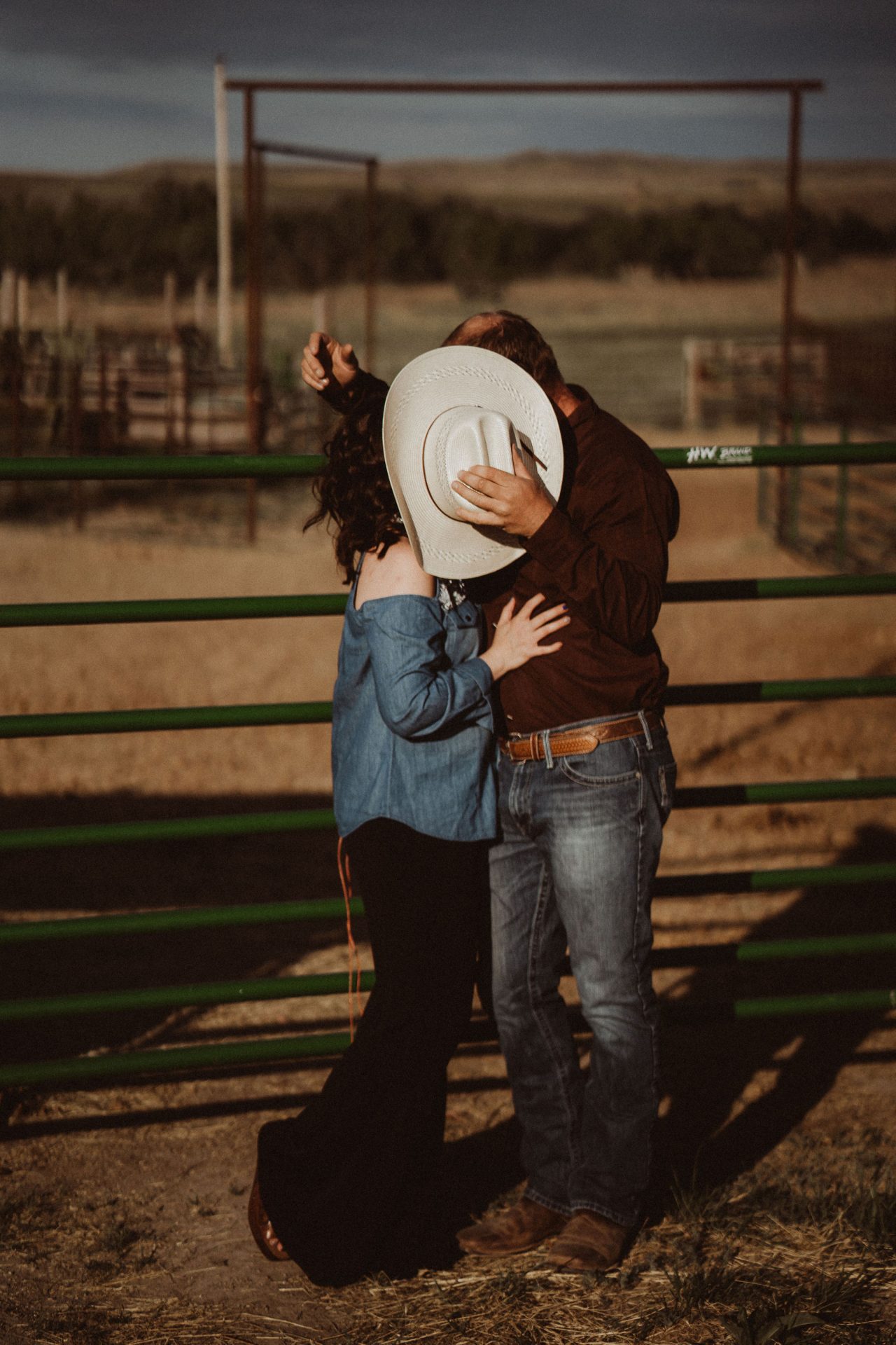 husband giving wife a kiss behind cowboy hat
